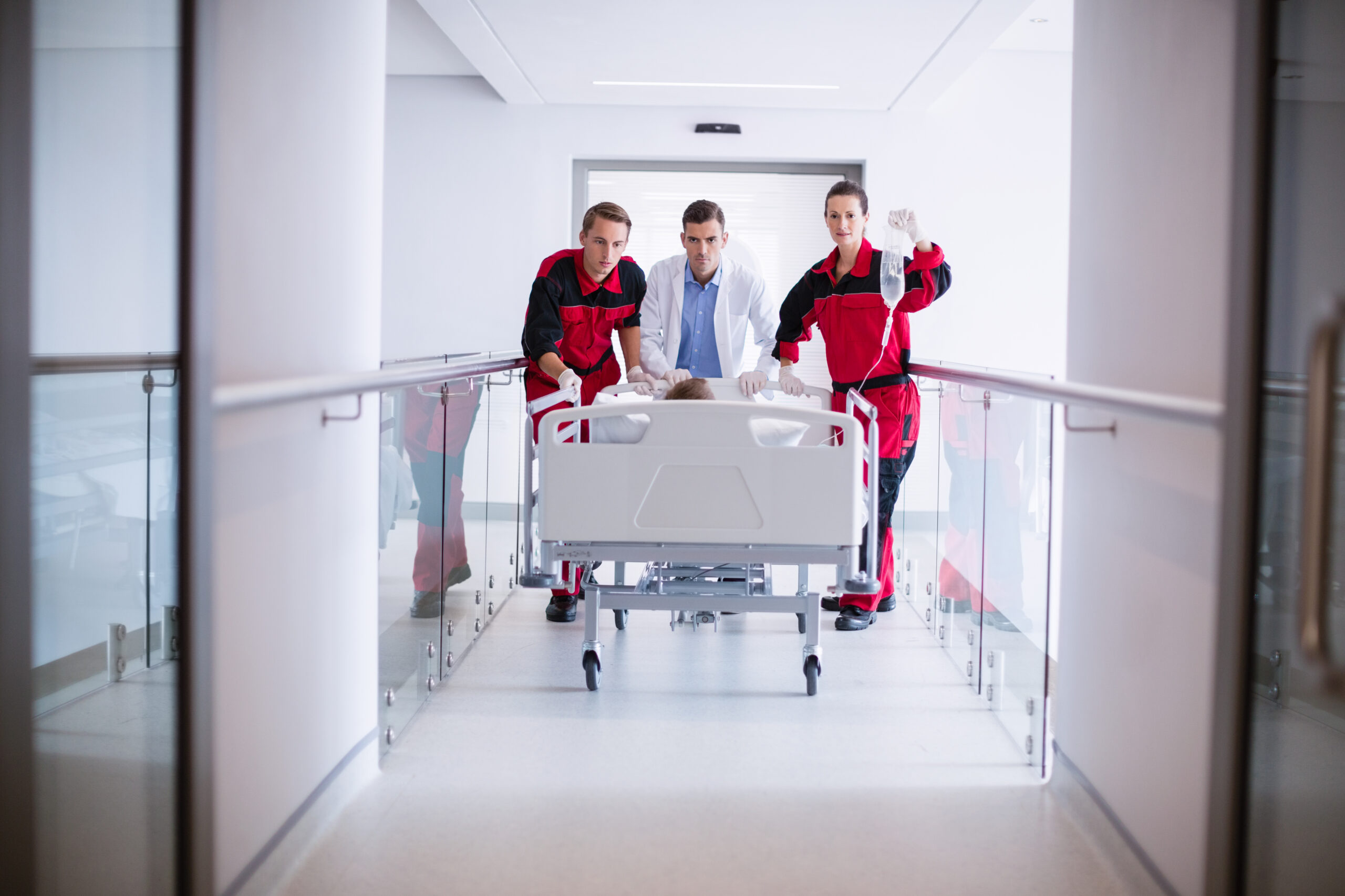 Doctors pushing emergency stretcher bed in corridor at hospital