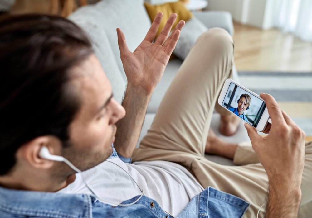 Close-up of a man having video call with a doctor over mobile phone while sitting at home.