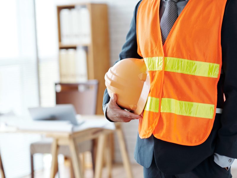 Cropped image of engineer with hardhat standing in office