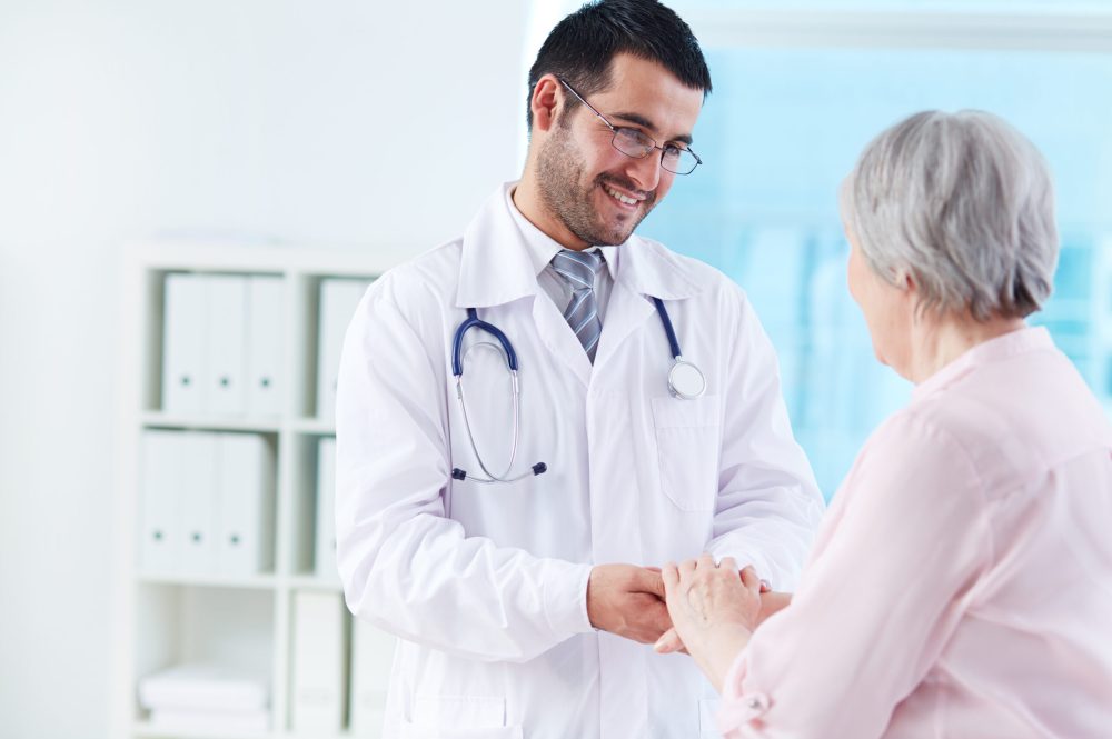 Confident doctor looking at his senior patient while speaking to her